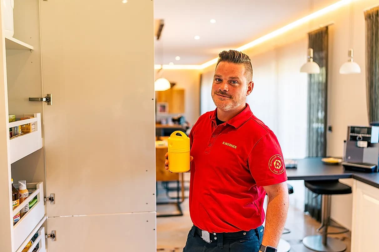 Mitarbeiter der Matuszak Hygiene an einem Küchenschrank mit Köderdose